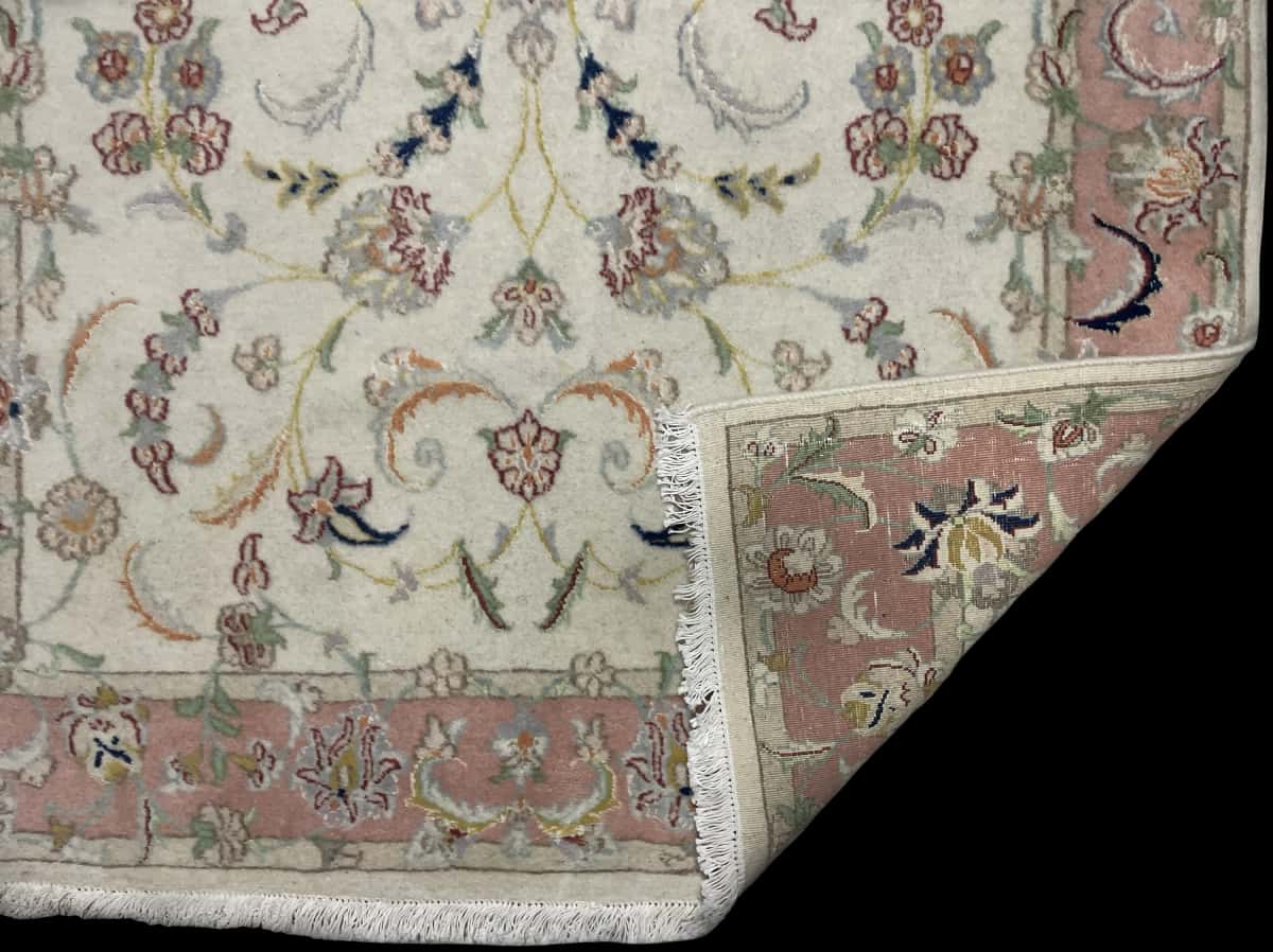 alfombra persa de estilo Tabriz en dimensiones 190 centímetros de largo por 124 centímetros de ancho con colores principalmente beige y rosa — Plegada