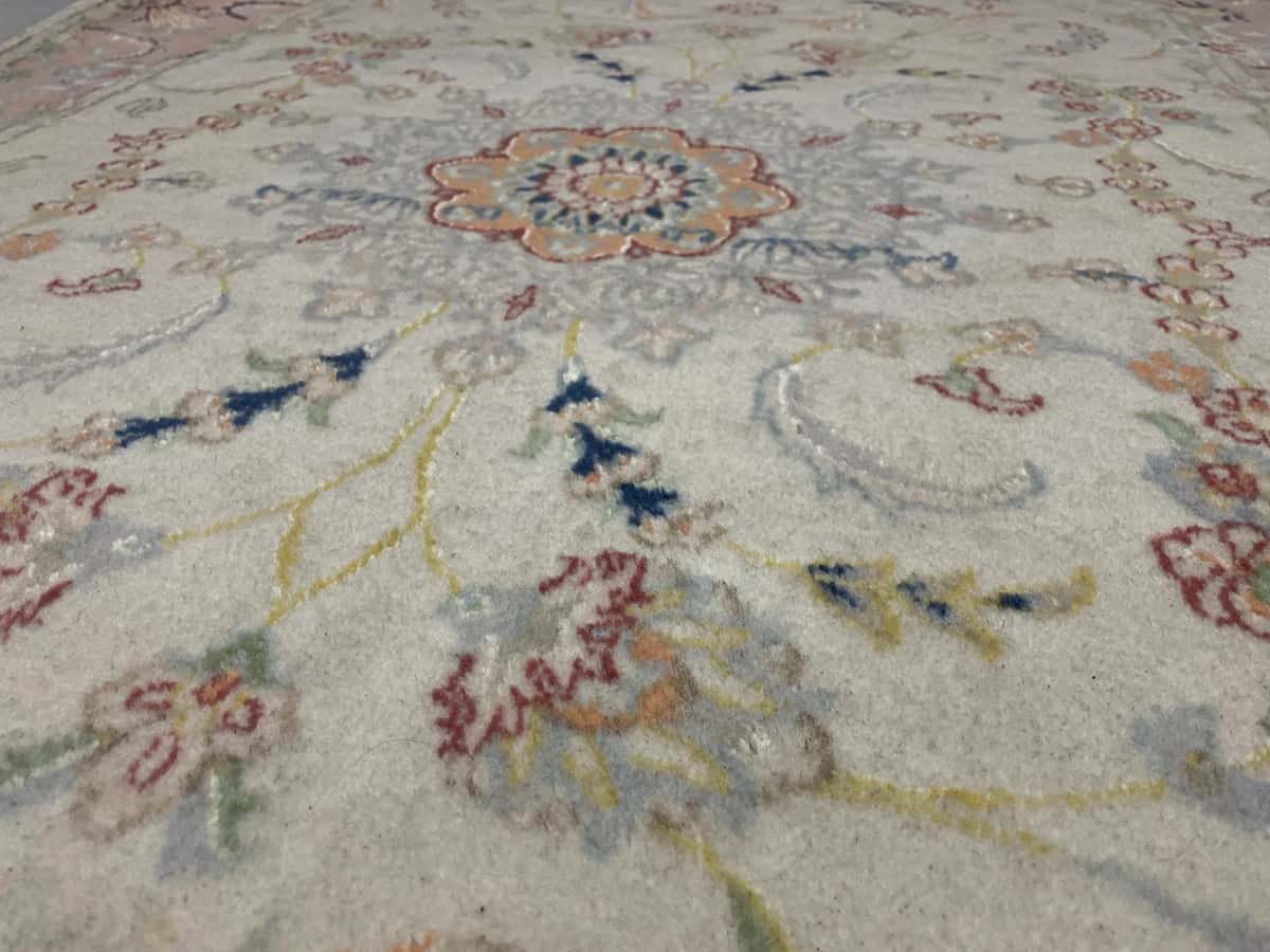 persischer Teppich im Tabriz Stil in den Maßen 190 Zentimeter Länge mal 124 Zentimeter Breite mit überwiegend beige und rosa Farben — Nahaufnahme der Textur