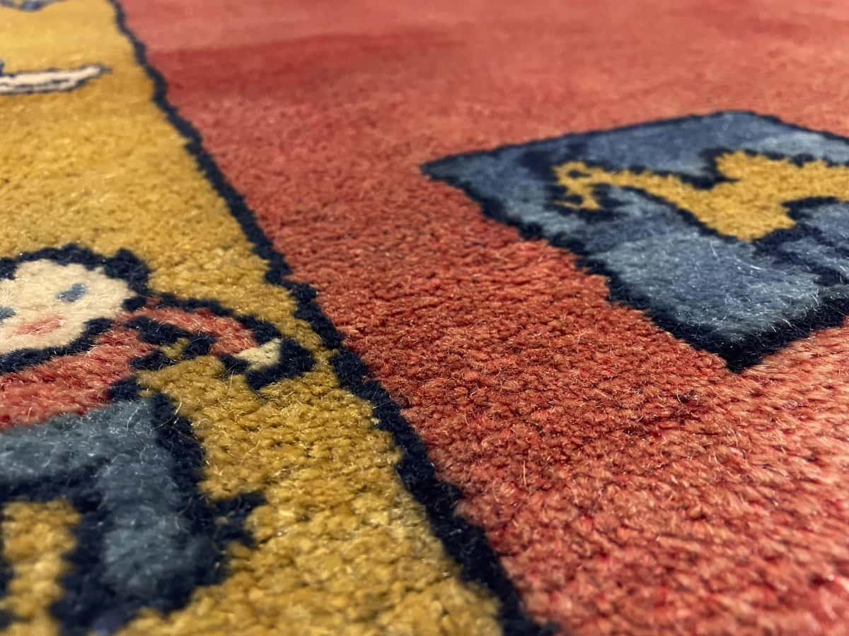 Persian rug of Gabbeh style in dimensions 155 centimeters length by 112 centimeters width with mainly red colors — Texture close-up