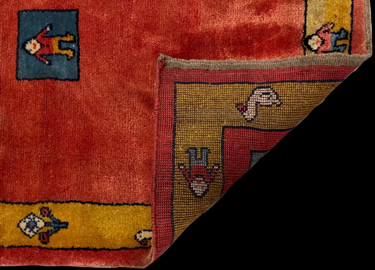 persischer Teppich im Gabbeh Stil in den Maßen 155 Zentimeter Länge mal 112 Zentimeter Breite mit überwiegend rot Farben — Gefaltet