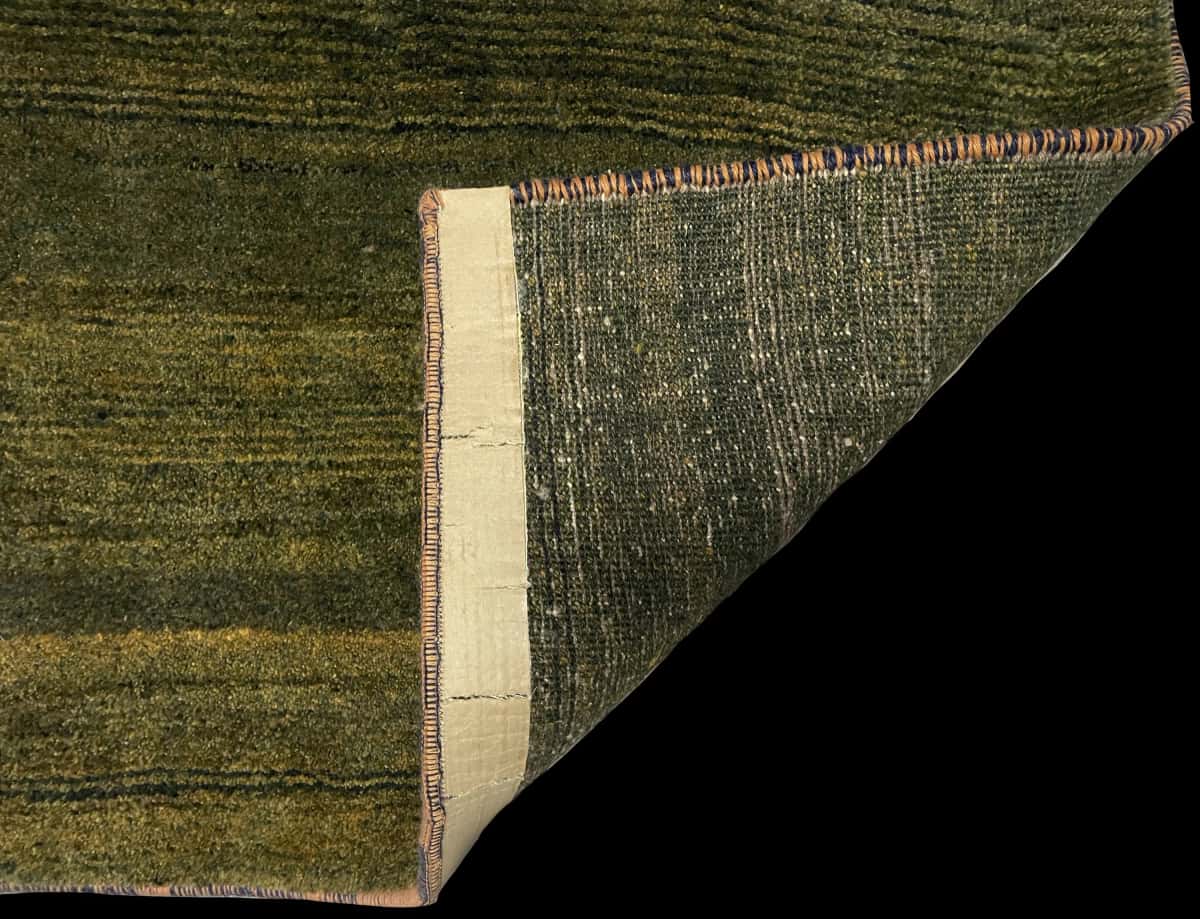 alfombra persa de estilo gabbeh en dimensiones 165 centímetros de largo por 75 centímetros de ancho con colores principalmente verde — Plegada