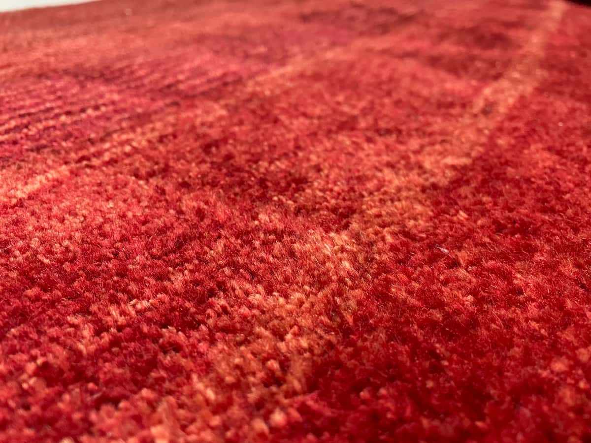 Persian rug of Gabbeh style in dimensions 156 centimeters length by 85 centimeters width with mainly red colors — Texture close-up