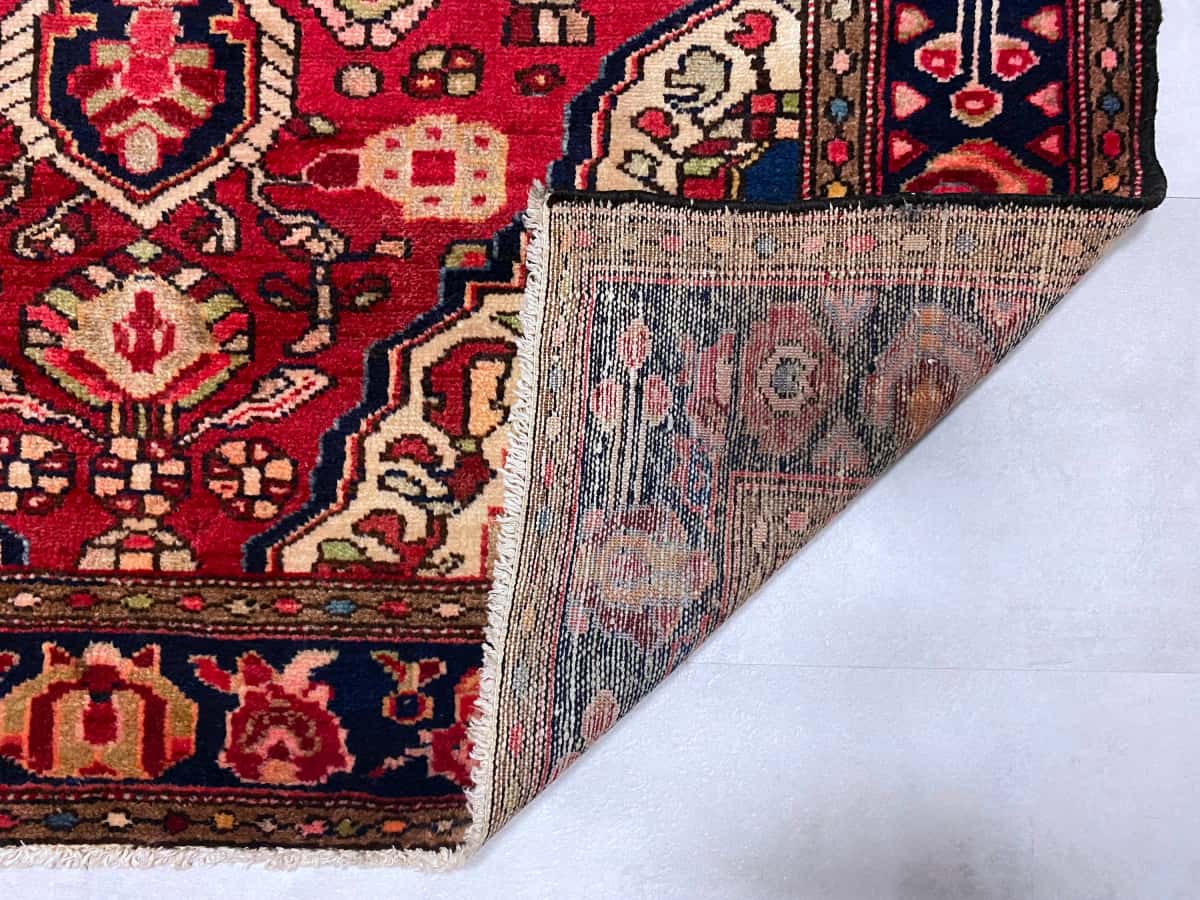 persischer Teppich in den Maßen 193 Zentimeter Länge mal 126 Zentimeter Breite mit überwiegend rot Farben — Gefaltet