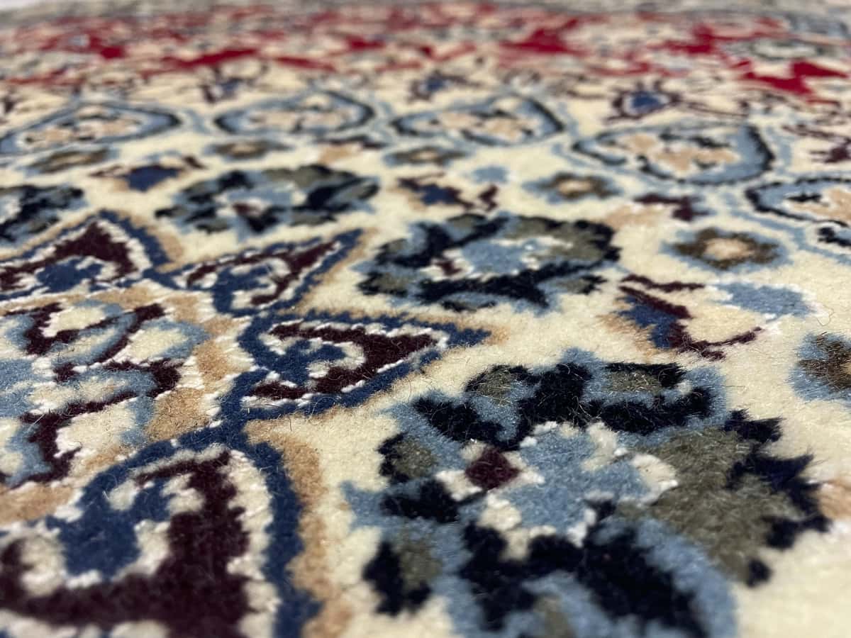Persian rug of Nain style in dimensions 196 centimeters length by 148 centimeters width with mainly red colors — Texture close-up