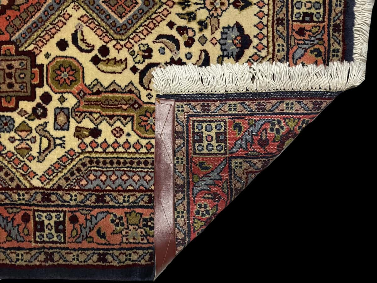 alfombra persa de estilo Hamadán en dimensiones 148 centímetros de largo por 98 centímetros de ancho con colores principalmente beige y naranja — Plegada