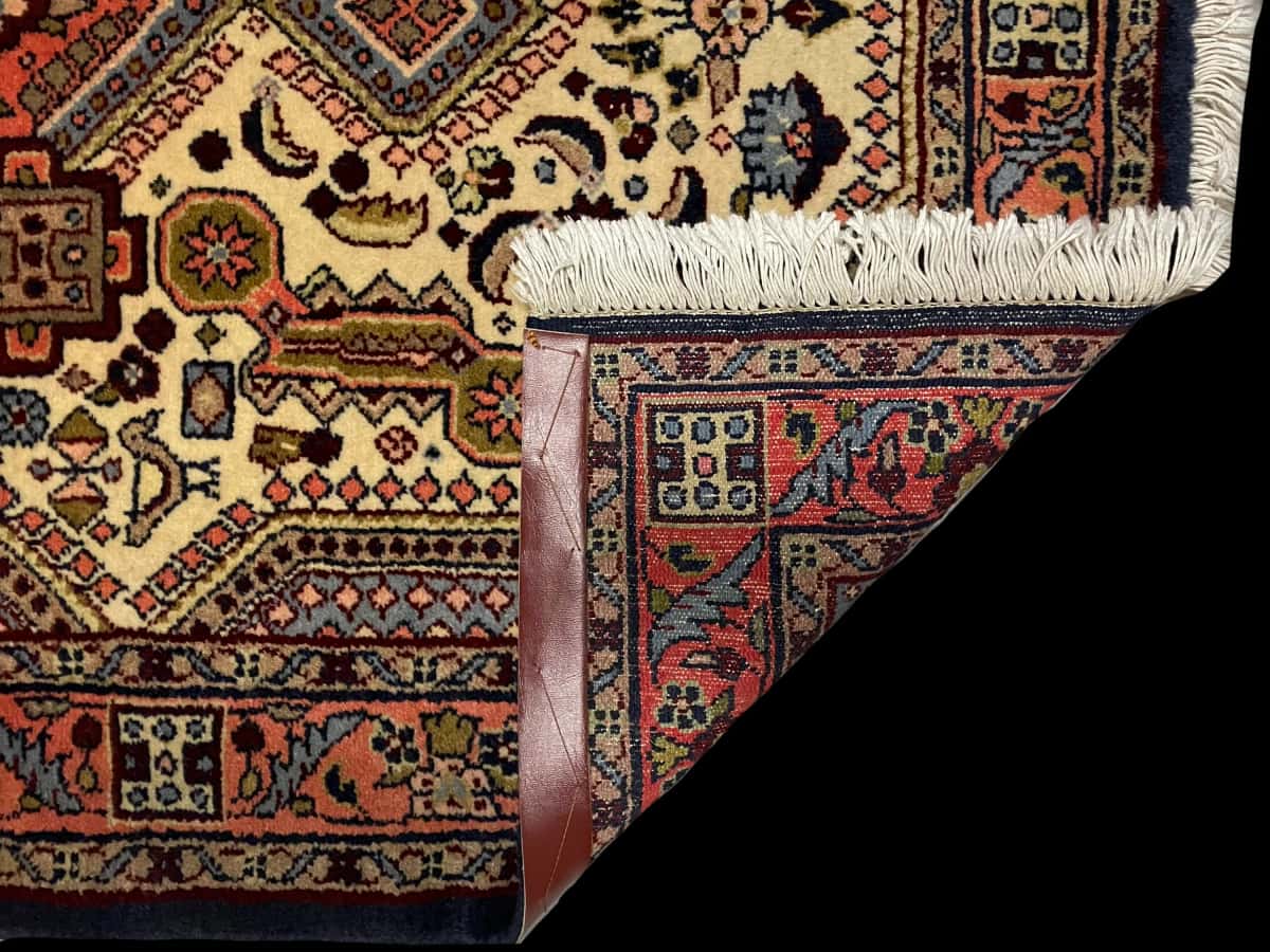 persischer Teppich im Hamadan Stil in den Maßen 148 Zentimeter Länge mal 98 Zentimeter Breite mit überwiegend beige und orange Farben — Gefaltet