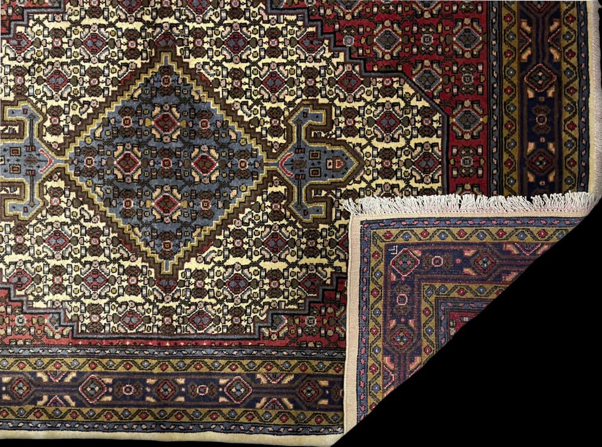 alfombra persa de estilo Hamadán en dimensiones 165 centímetros de largo por 112 centímetros de ancho con colores principalmente rojo y beige — Plegada