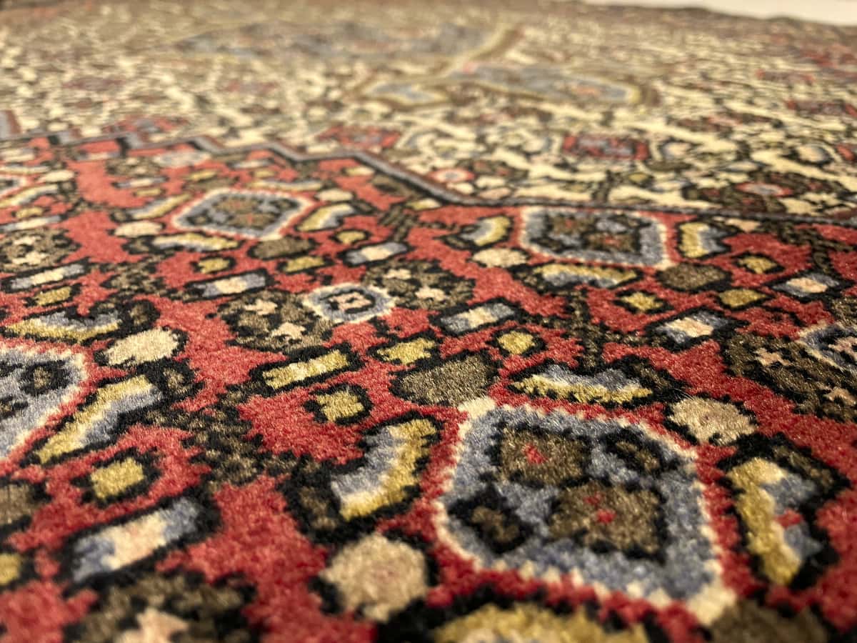 alfombra persa de estilo Hamadán en dimensiones 165 centímetros de largo por 112 centímetros de ancho con colores principalmente rojo y beige — Primer plano de la textura