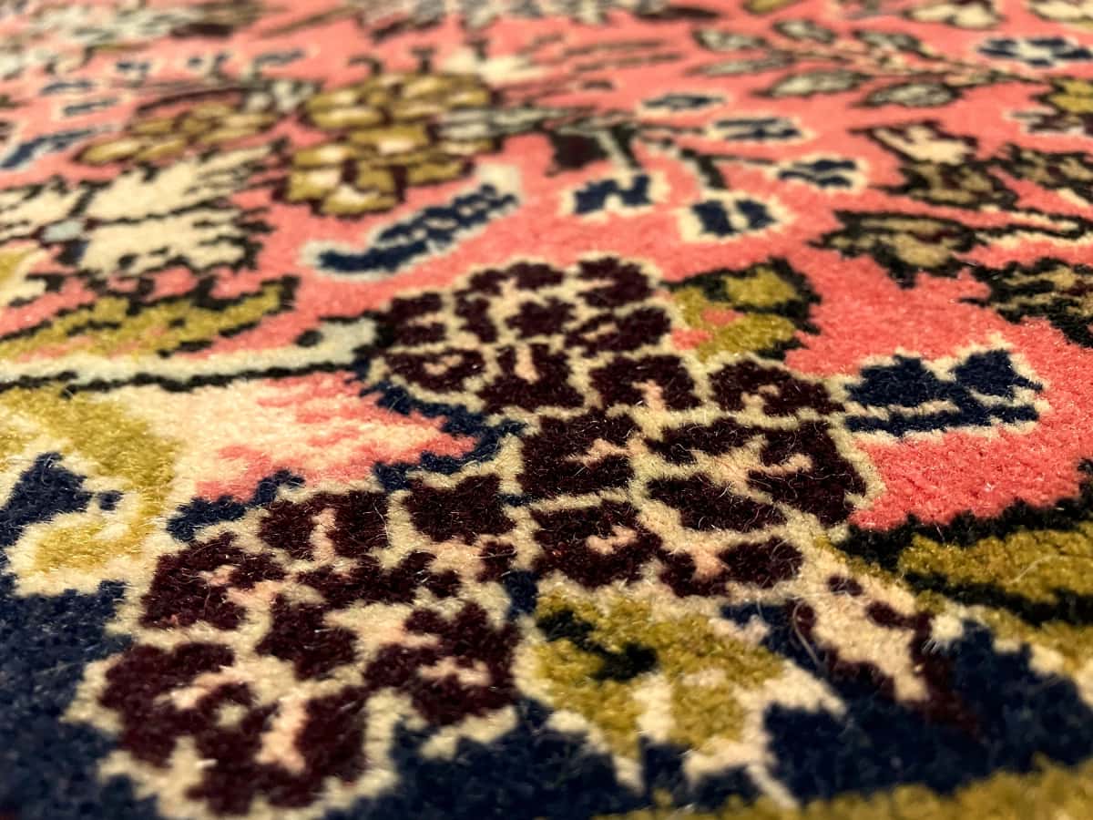 persischer Teppich im Hamadan Stil in den Maßen 150 Zentimeter Länge mal 100 Zentimeter Breite mit überwiegend rosa und rot Farben — Nahaufnahme der Textur
