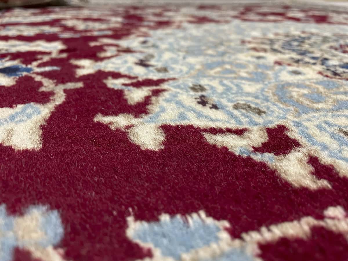 Persian rug of Nain style in dimensions 203 centimeters length by 145 centimeters width with mainly red colors — Texture close-up