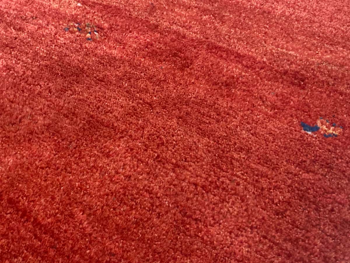 persischer Teppich im Gabbeh Stil in den Maßen 170 Zentimeter Länge mal 110 Zentimeter Breite mit überwiegend rot Farben — Nahaufnahme der Textur