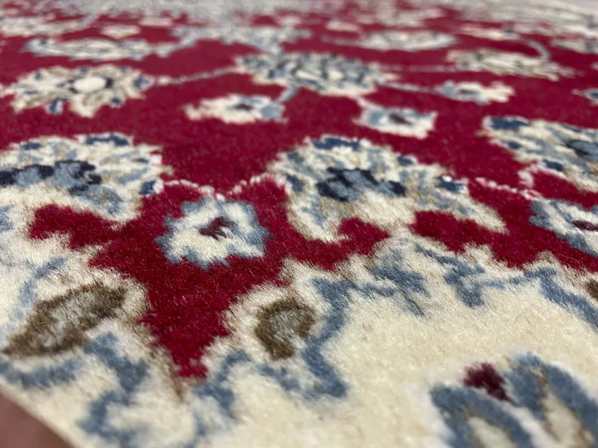Persian rug of Nain style in dimensions 205 centimeters length by 117 centimeters width with mainly red colors — Texture close-up