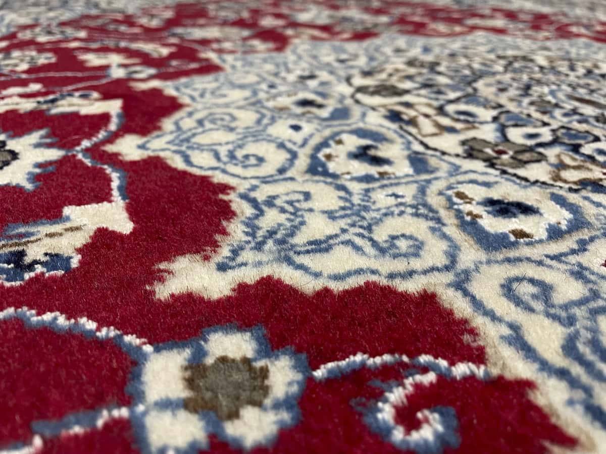 Persian rug of Nain style in dimensions 203 centimeters length by 140 centimeters width with mainly red and blue colors — Texture close-up