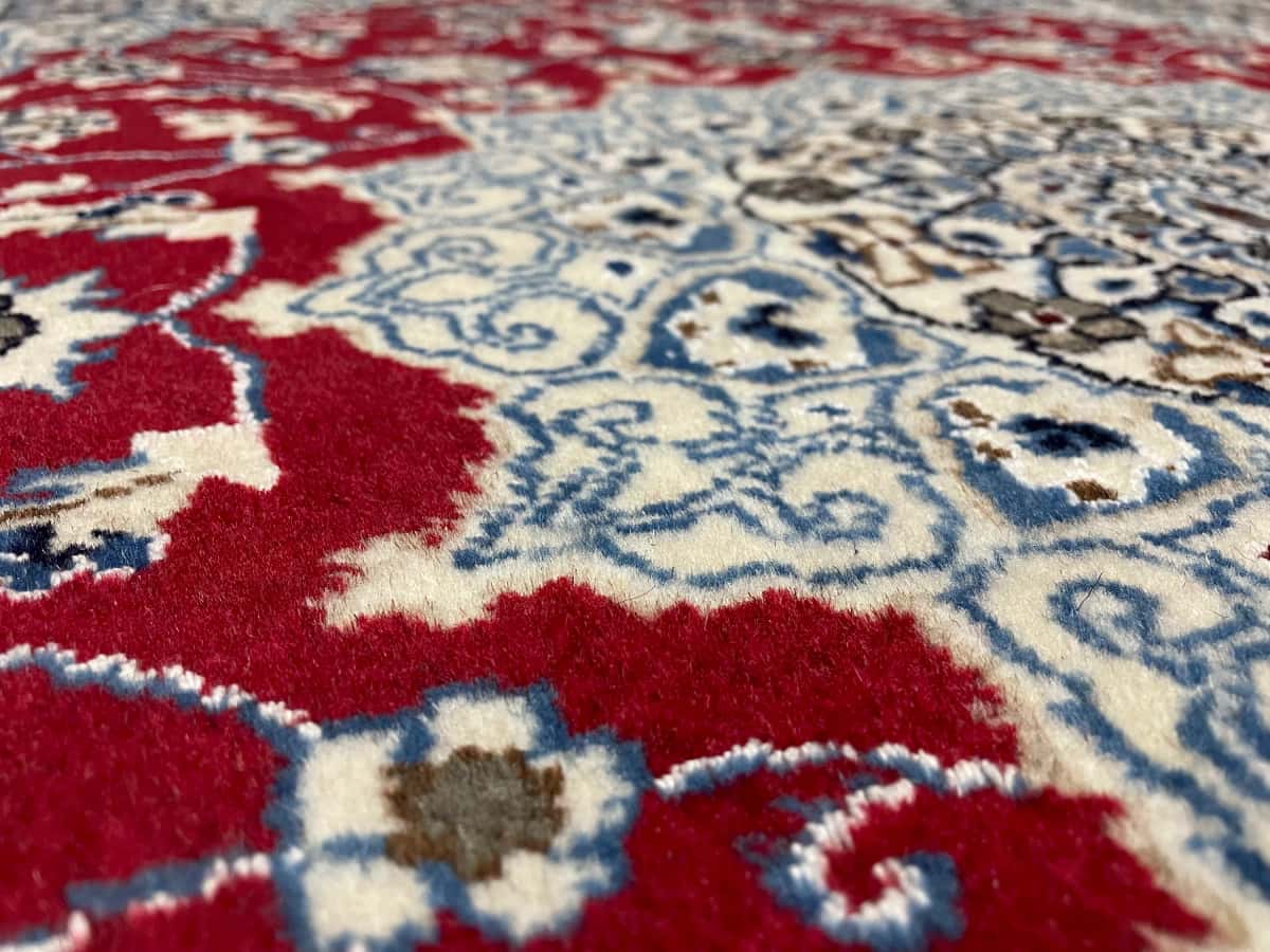 persischer Teppich im Nain Stil in den Maßen 203 Zentimeter Länge mal 140 Zentimeter Breite mit überwiegend rot und blau Farben — Nahaufnahme der Textur