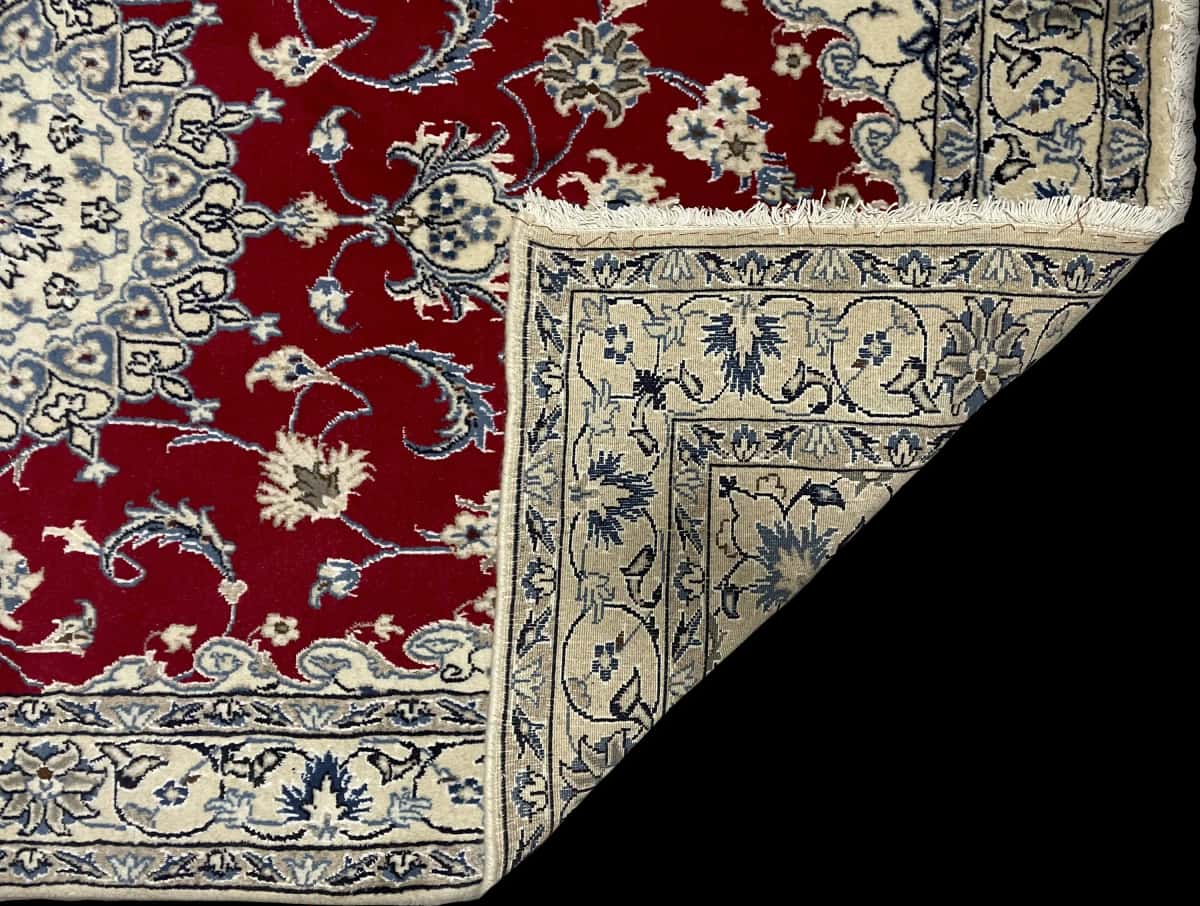 alfombra persa de estilo Nain en dimensiones 200 centímetros de largo por 118 centímetros de ancho con colores principalmente rojo — Plegada