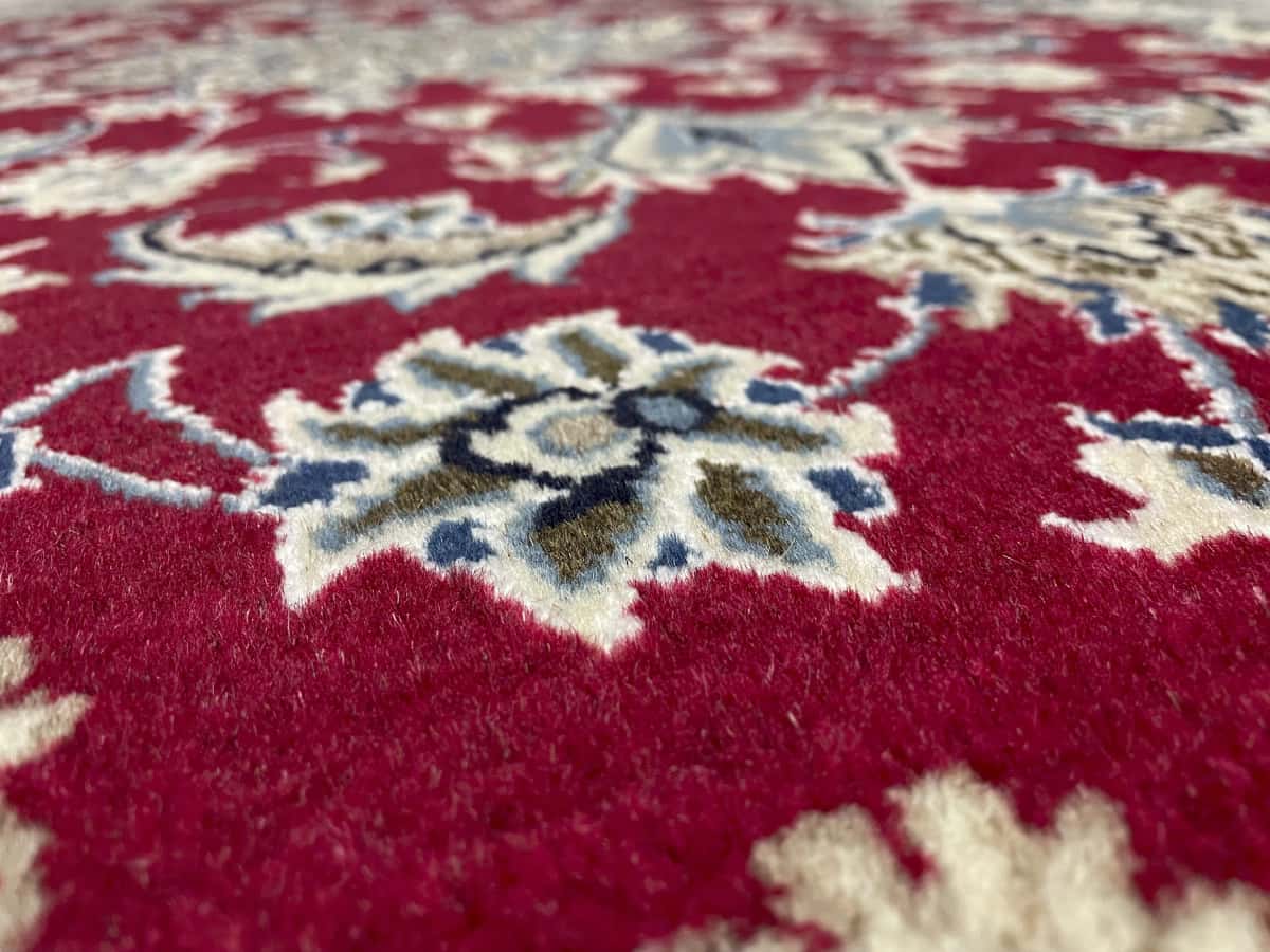 Persian rug of Nain style in dimensions 195 centimeters length by 115 centimeters width with mainly red colors — Texture close-up