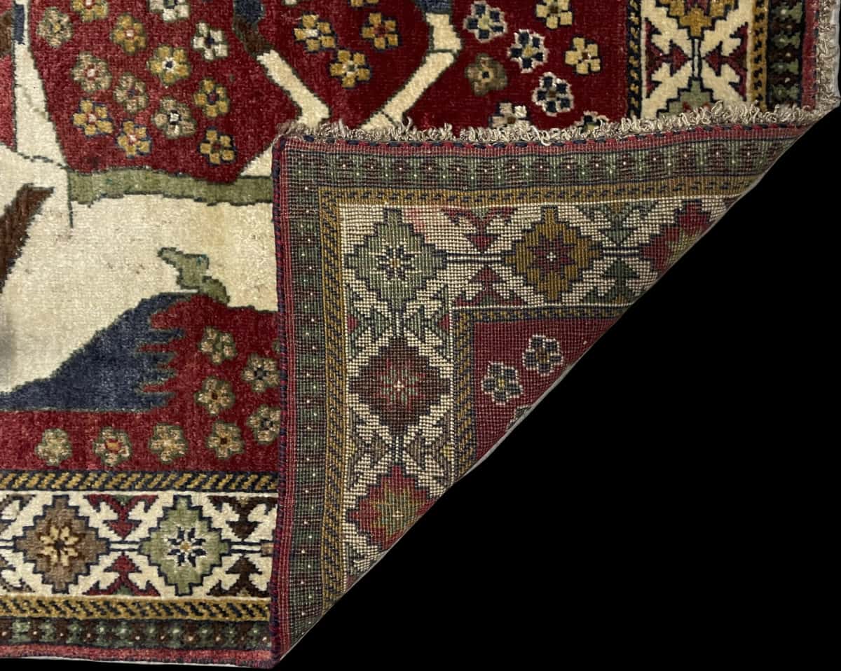alfombra persa de estilo gabbeh en dimensiones 203 centímetros de largo por 96 centímetros de ancho con colores principalmente rojo — Plegada