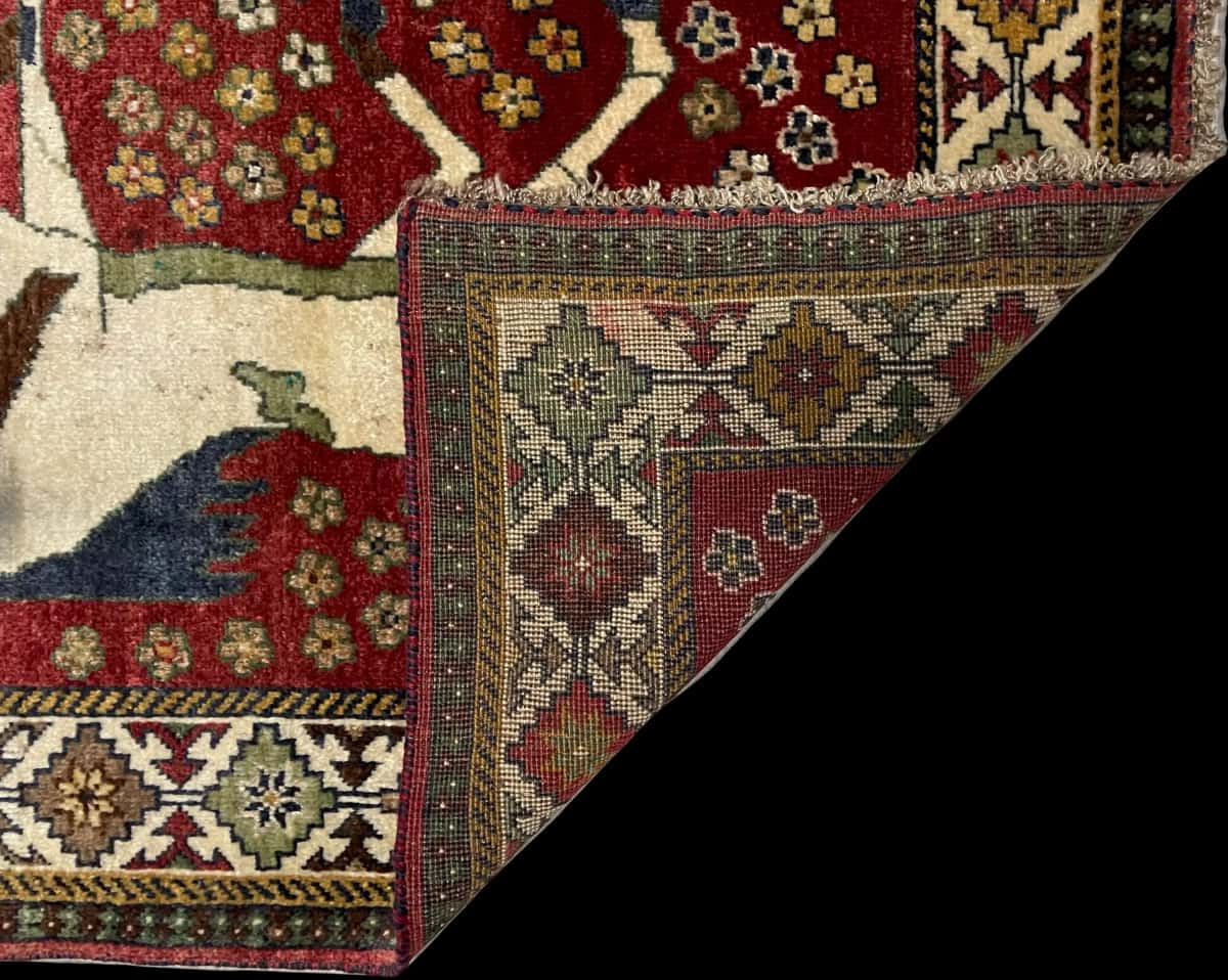 alfombra persa de estilo gabbeh en dimensiones 203 centímetros de largo por 96 centímetros de ancho con colores principalmente rojo — Plegada