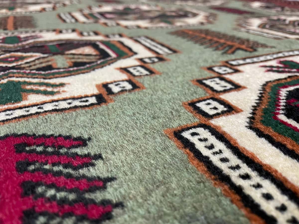 Persian rug of Turkoman style in dimensions 193 centimeters length by 130 centimeters width with mainly red and green colors — Texture close-up