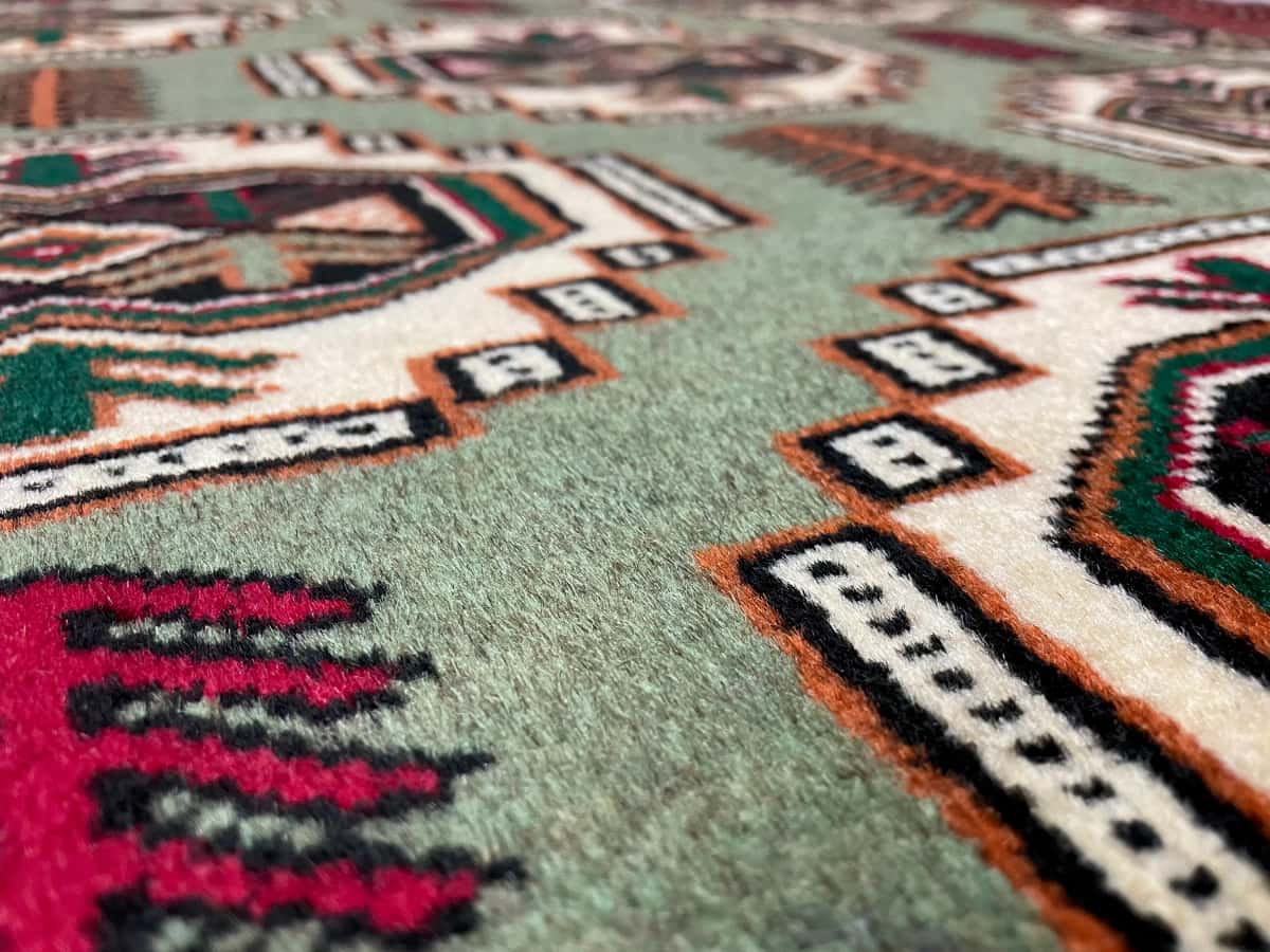 persischer Teppich im turkmenischer Stil in den Maßen 193 Zentimeter Länge mal 130 Zentimeter Breite mit überwiegend rot und grün Farben — Nahaufnahme der Textur