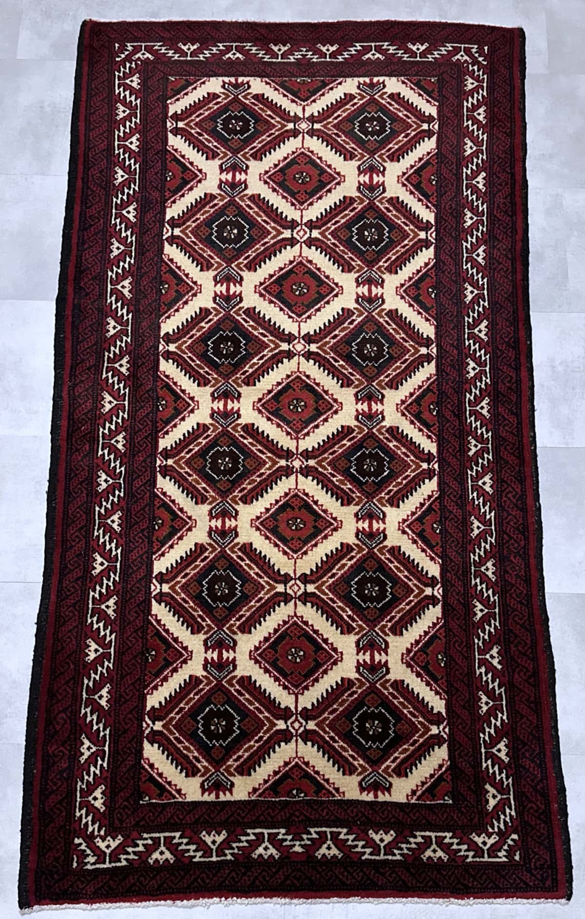 persischer Teppich in den Maßen 190 Zentimeter Länge mal 100 Zentimeter Breite mit überwiegend rot und beige Farben — Perspektive