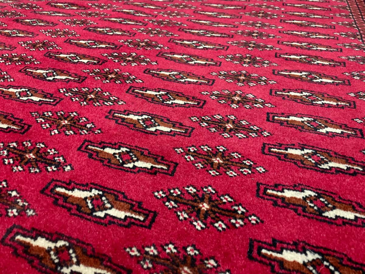 persischer Teppich im turkmenischer Stil in den Maßen 196 Zentimeter Länge mal 132 Zentimeter Breite mit überwiegend rot Farben — Nahaufnahme der Textur
