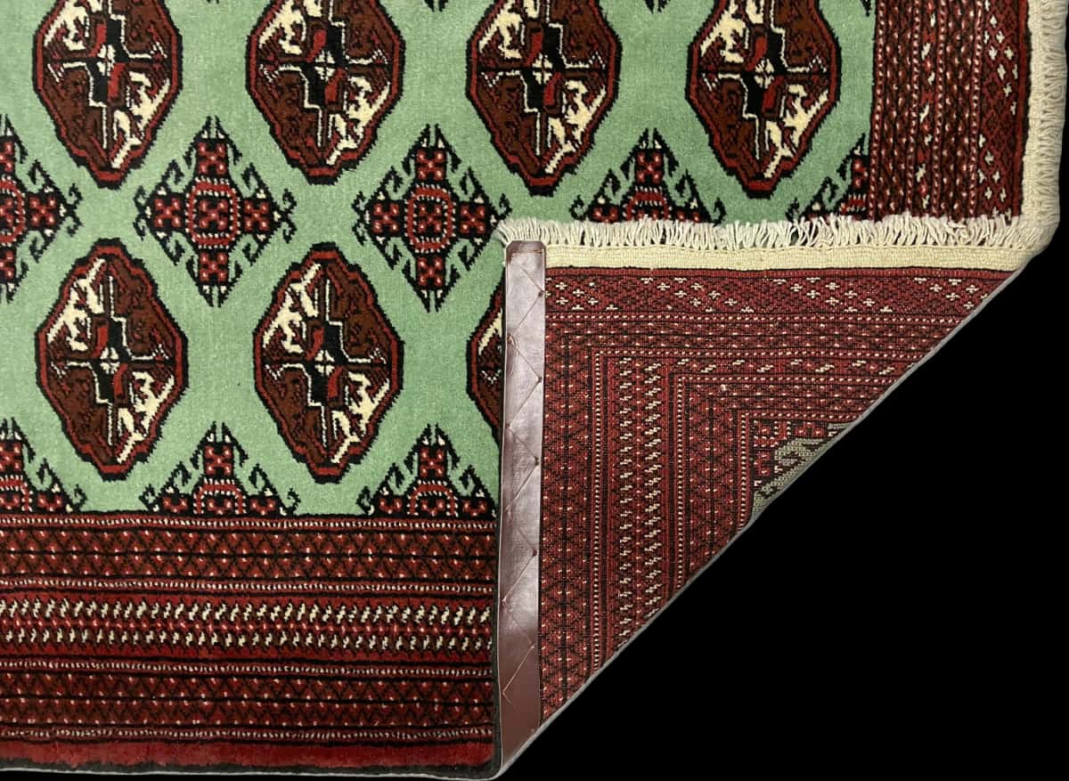 alfombra persa de estilo turcomana en dimensiones 198 centímetros de largo por 132 centímetros de ancho con colores principalmente verde — Plegada
