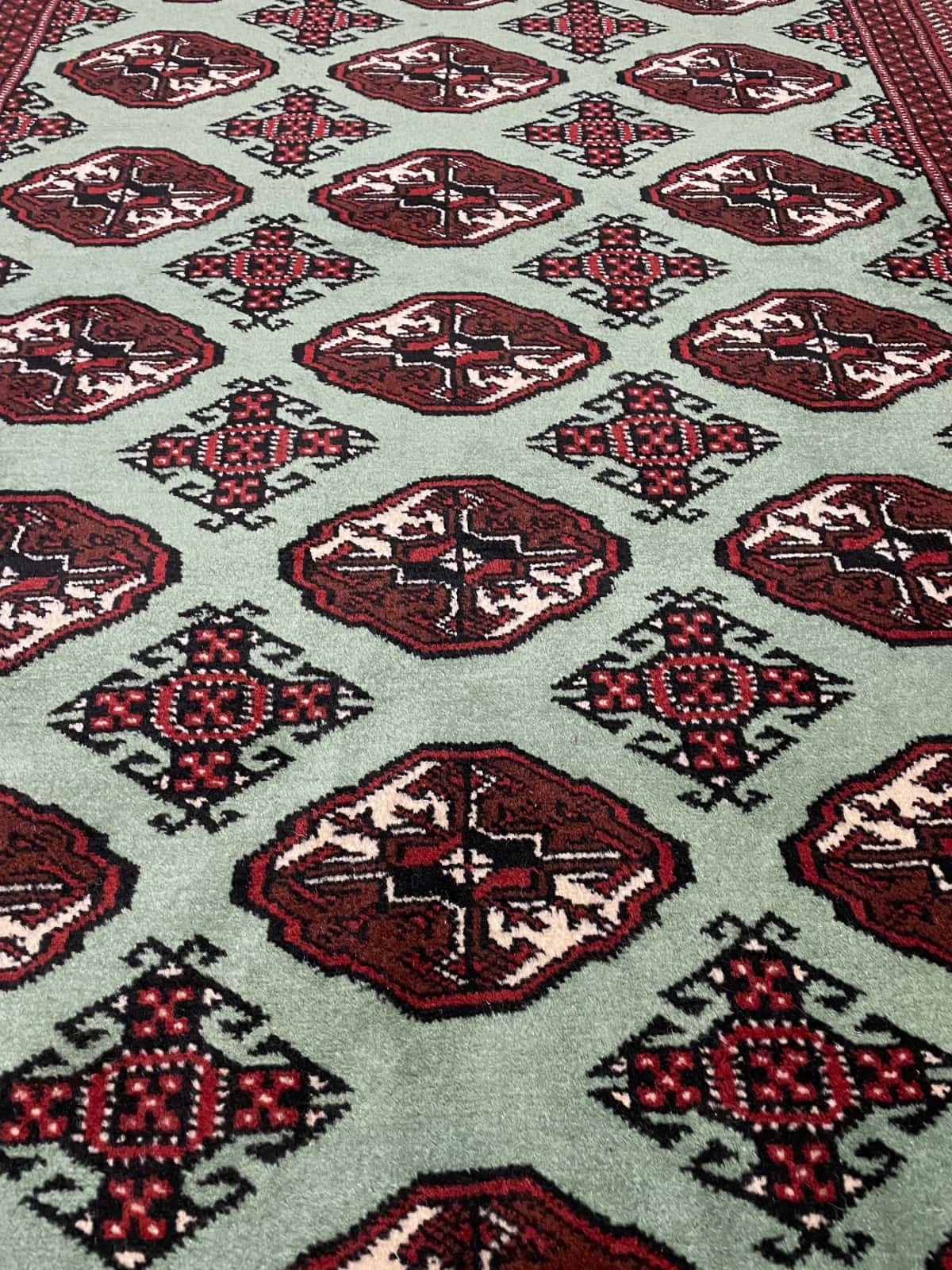 alfombra persa de estilo turcomana en dimensiones 198 centímetros de largo por 132 centímetros de ancho con colores principalmente verde — Primer plano de la textura