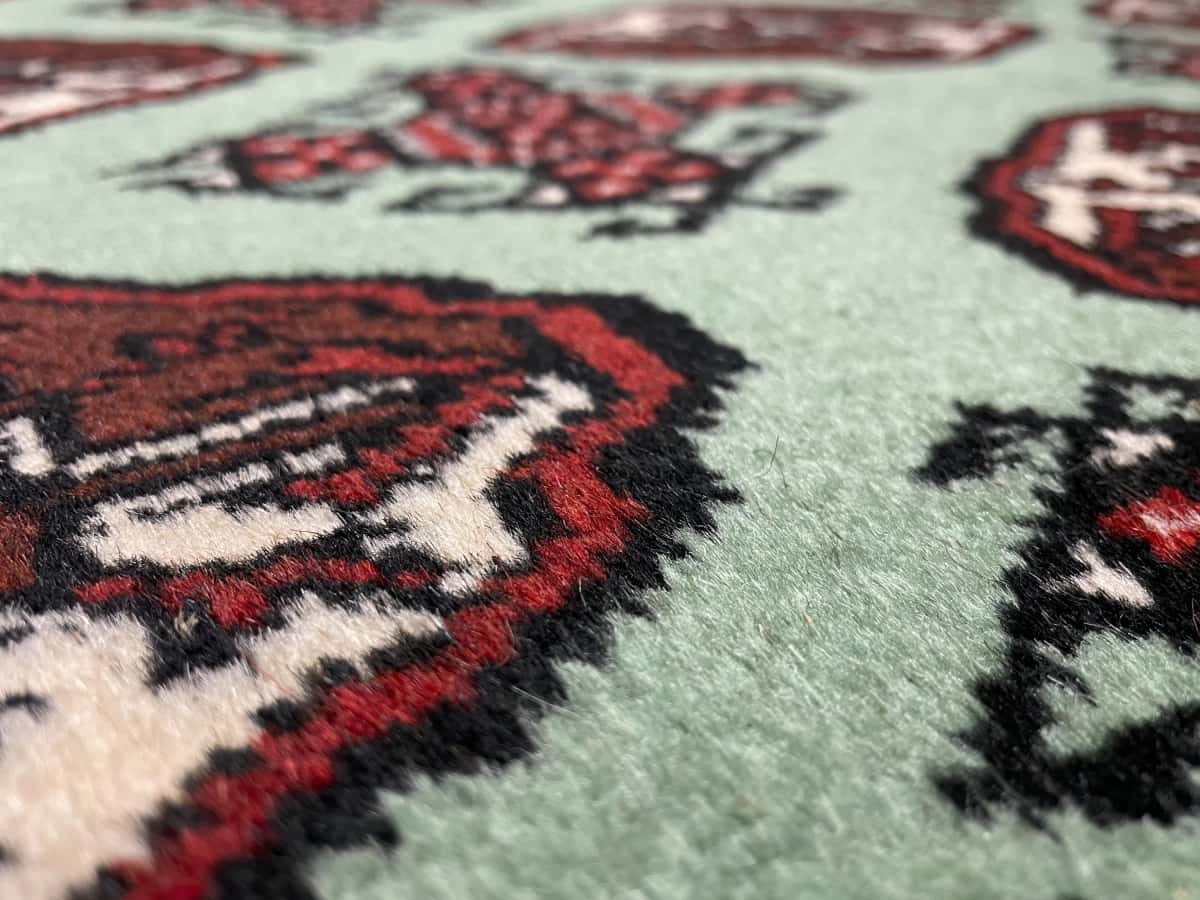 alfombra persa de estilo turcomana en dimensiones 198 centímetros de largo por 132 centímetros de ancho con colores principalmente verde — Primer plano de la textura