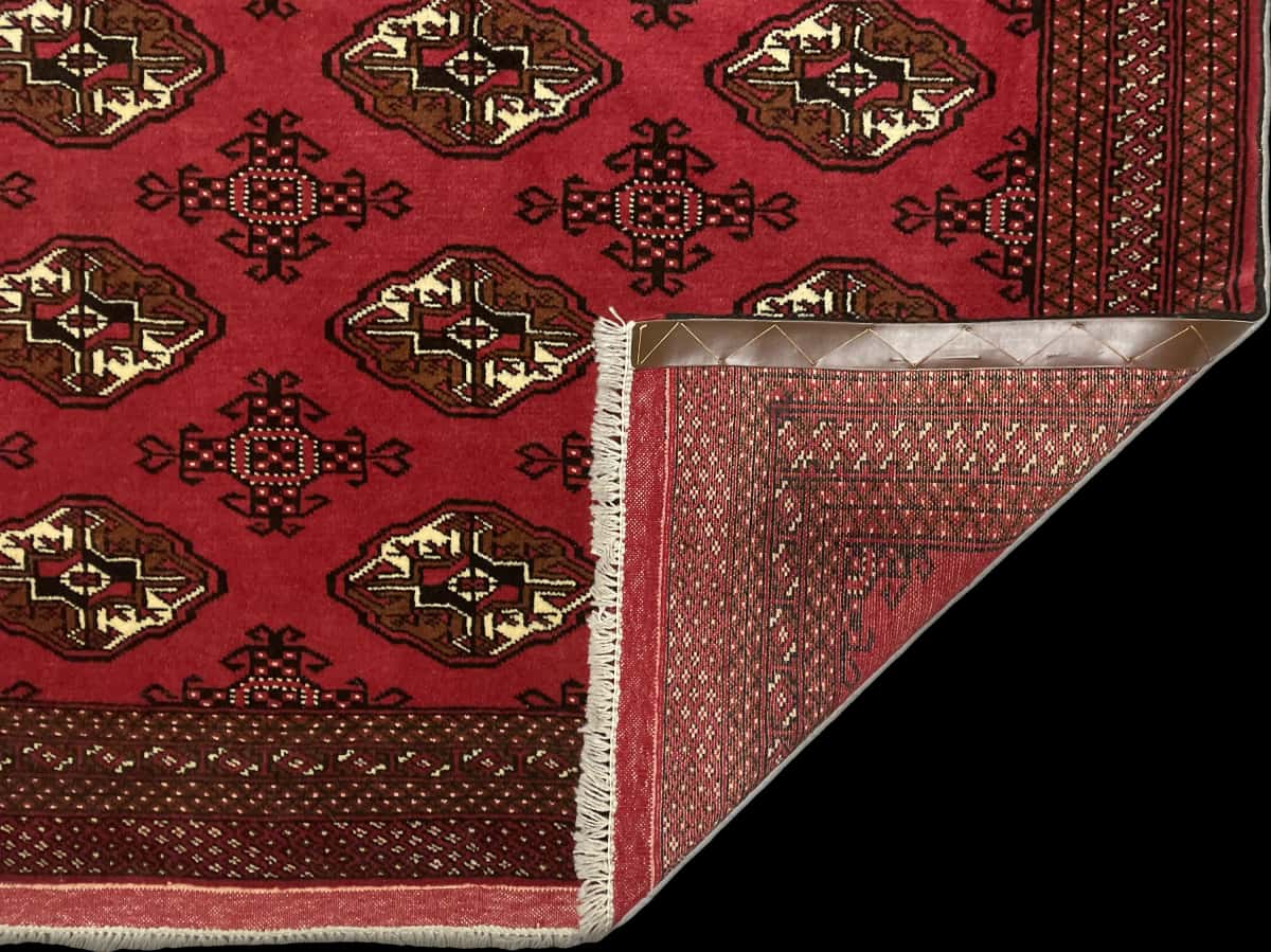 alfombra persa de estilo turcomana en dimensiones 203 centímetros de largo por 132 centímetros de ancho con colores principalmente rojo — Plegada