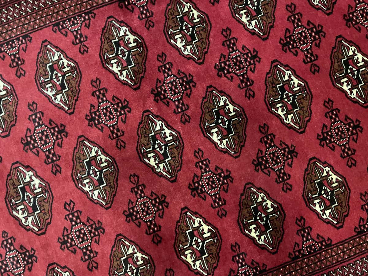 alfombra persa de estilo turcomana en dimensiones 203 centímetros de largo por 132 centímetros de ancho con colores principalmente rojo — Primer plano de la textura