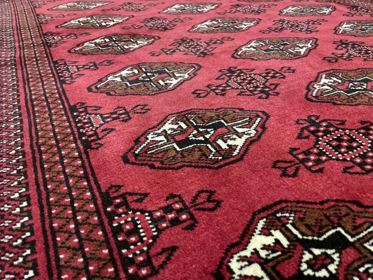 alfombra persa de estilo turcomana en dimensiones 203 centímetros de largo por 132 centímetros de ancho con colores principalmente rojo — Primer plano de la textura