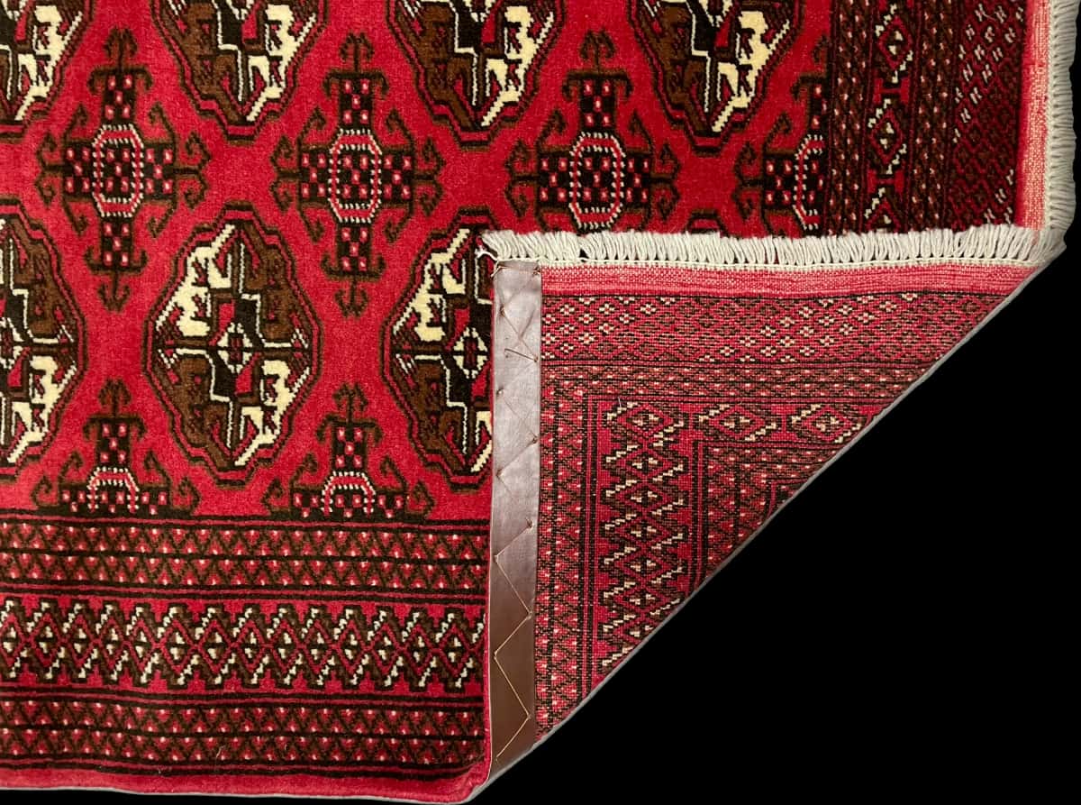 persischer Teppich im turkmenischer Stil in den Maßen 196 Zentimeter Länge mal 135 Zentimeter Breite mit überwiegend rot Farben — Gefaltet