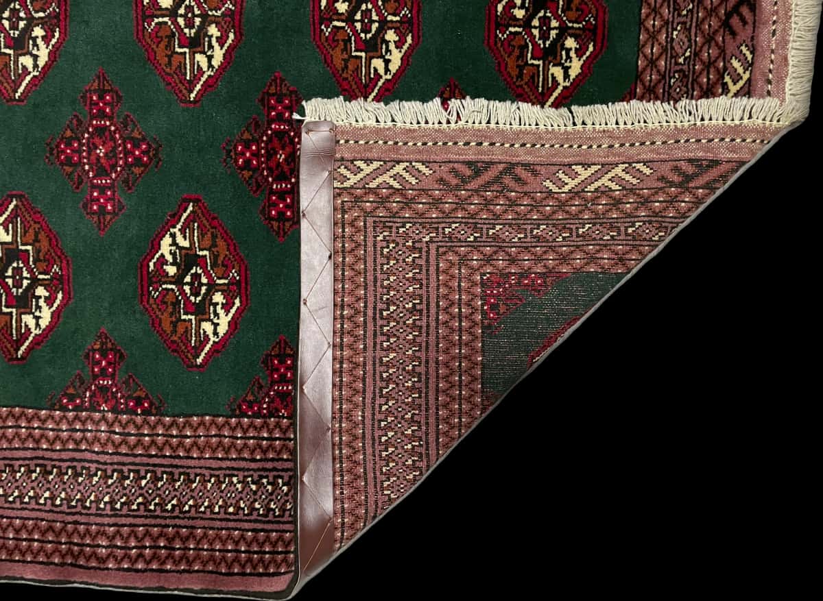 alfombra persa de estilo turcomana en dimensiones 196 centímetros de largo por 132 centímetros de ancho con colores principalmente verde — Plegada