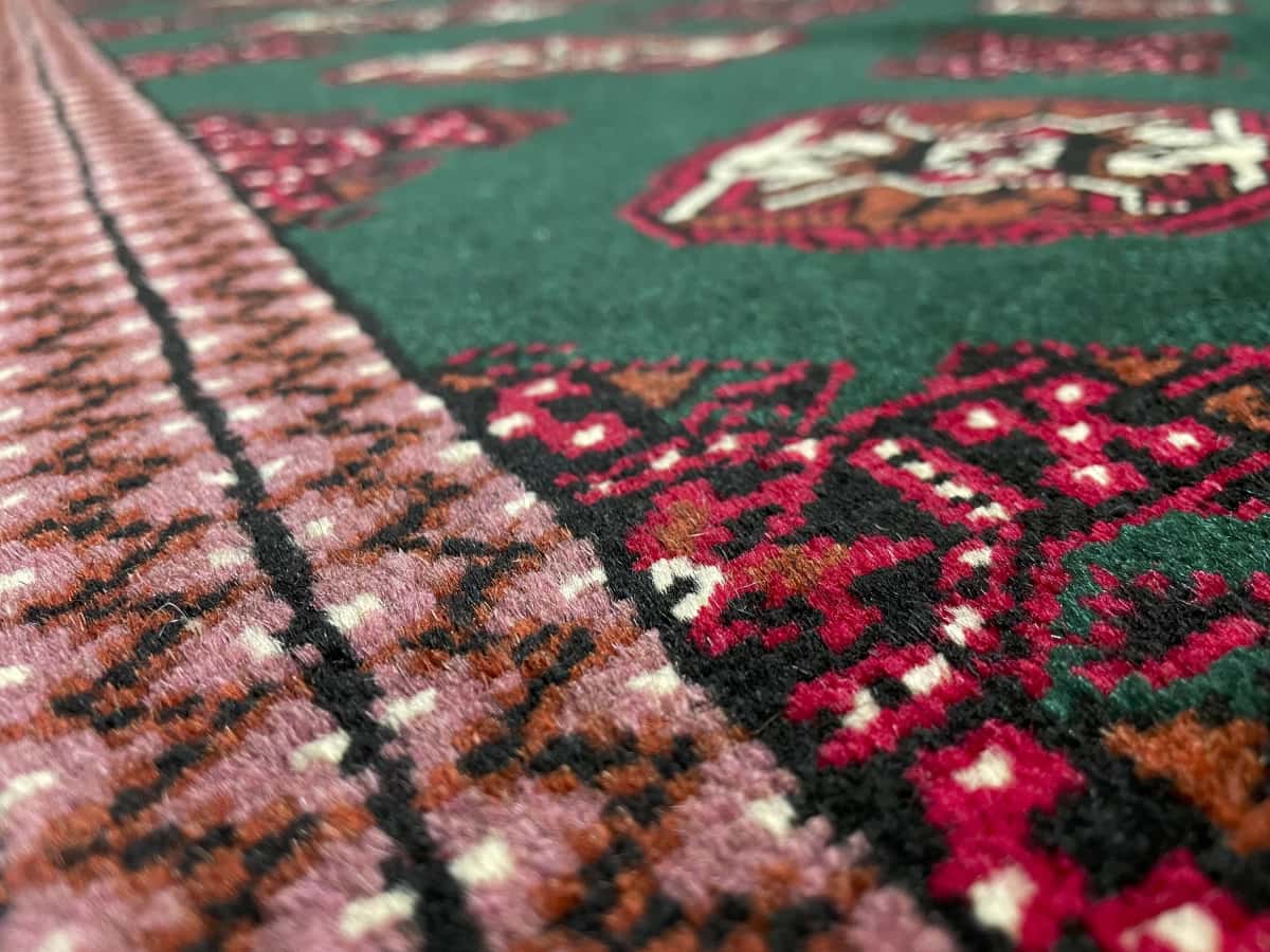 alfombra persa de estilo turcomana en dimensiones 196 centímetros de largo por 132 centímetros de ancho con colores principalmente verde — Primer plano de la textura