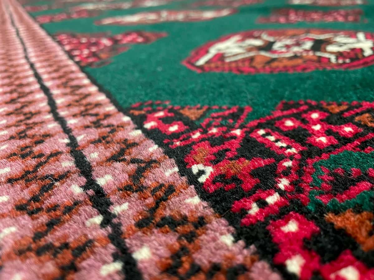 Persian rug of Turkoman style in dimensions 196 centimeters length by 132 centimeters width with mainly green colors — Texture close-up