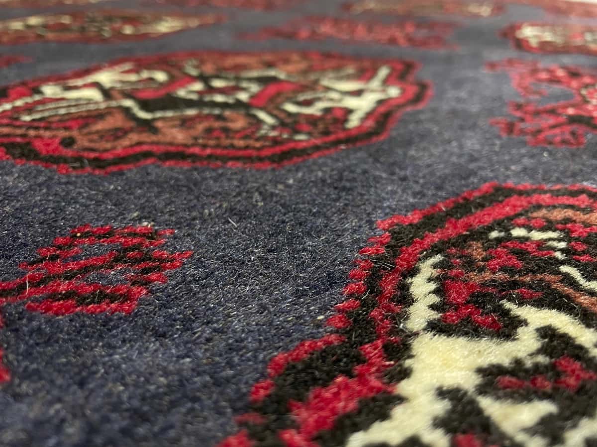Persian rug of Turkoman style in dimensions 179 centimeters length by 130 centimeters width with mainly red and blue colors — Texture close-up
