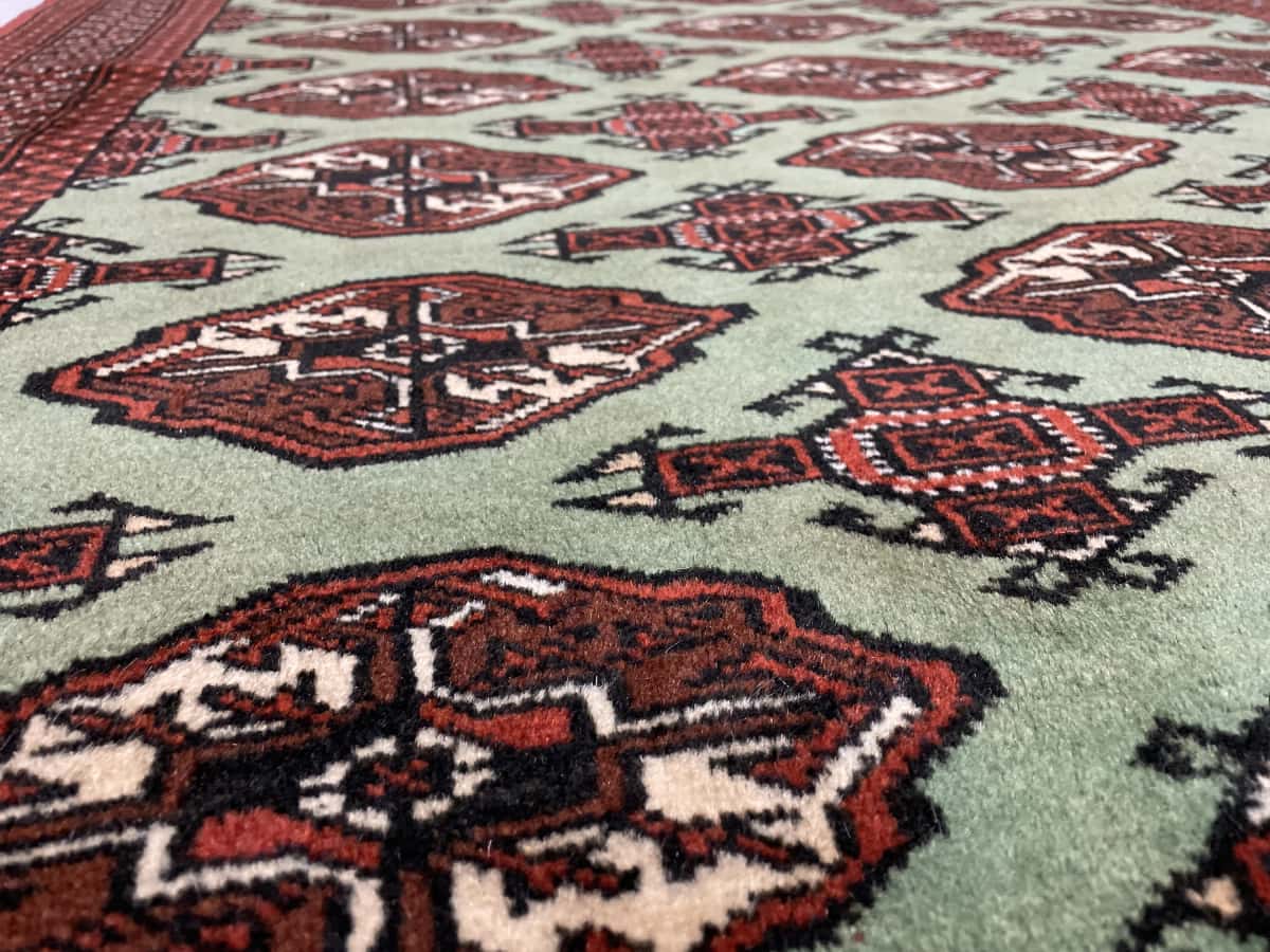 alfombra persa de estilo turcomana en dimensiones 188 centímetros de largo por 130 centímetros de ancho con colores principalmente verde — Primer plano de la textura