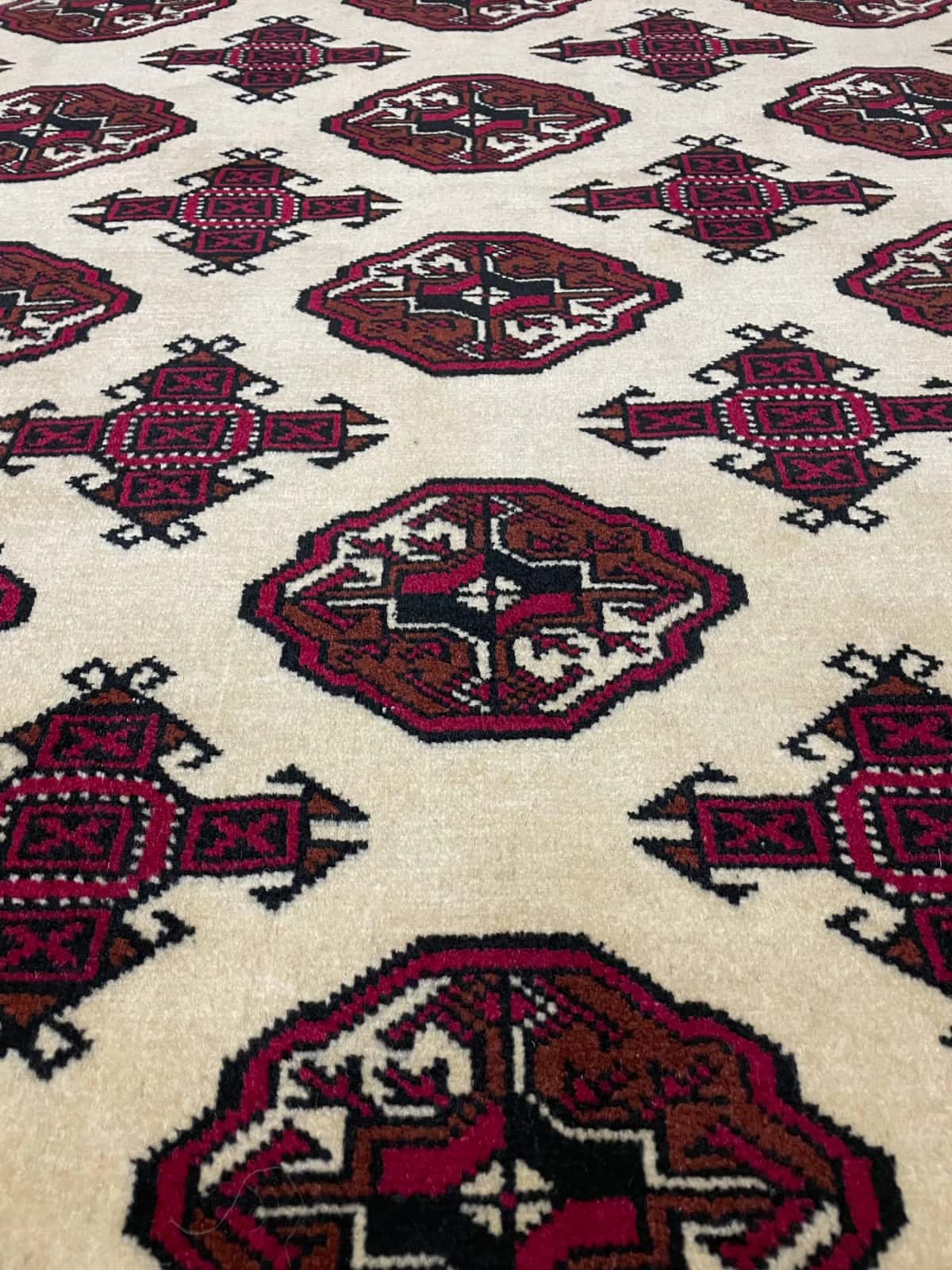Persian rug of Turkoman style in dimensions 196 centimeters length by 136 centimeters width with mainly beige and red colors — Texture close-up