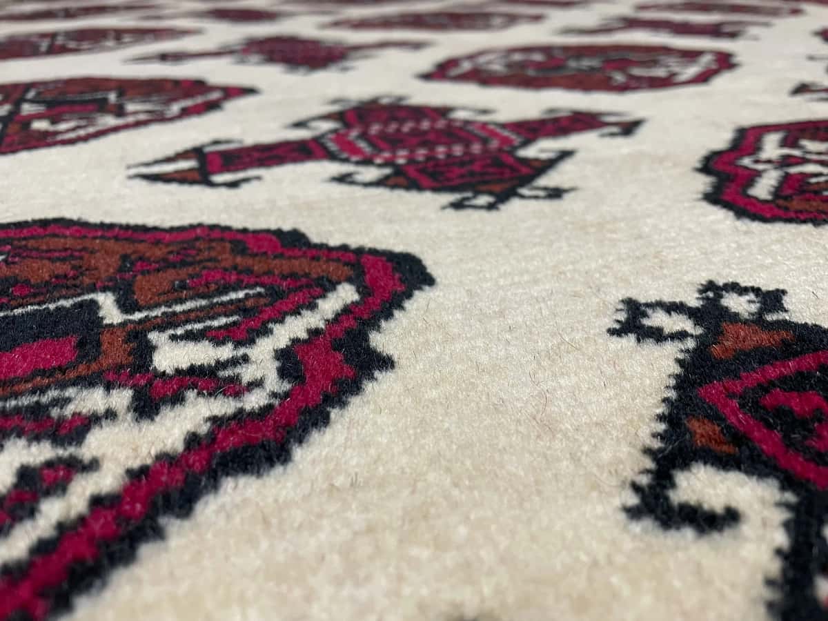 Persian rug of Turkoman style in dimensions 196 centimeters length by 136 centimeters width with mainly beige and red colors — Texture close-up