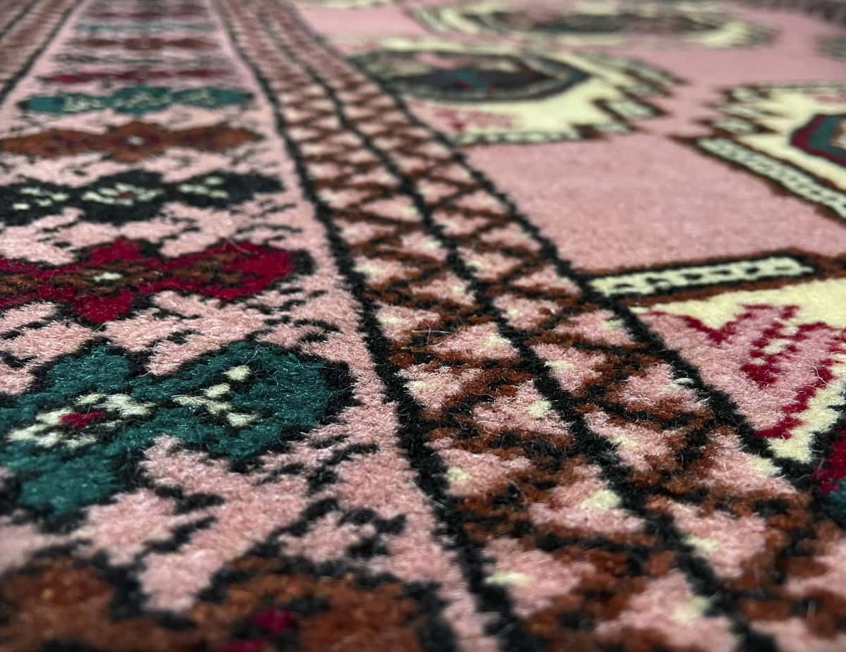 Persian rug of Turkoman style in dimensions 125 centimeters length by 85 centimeters width with mainly pink colors — Texture close-up