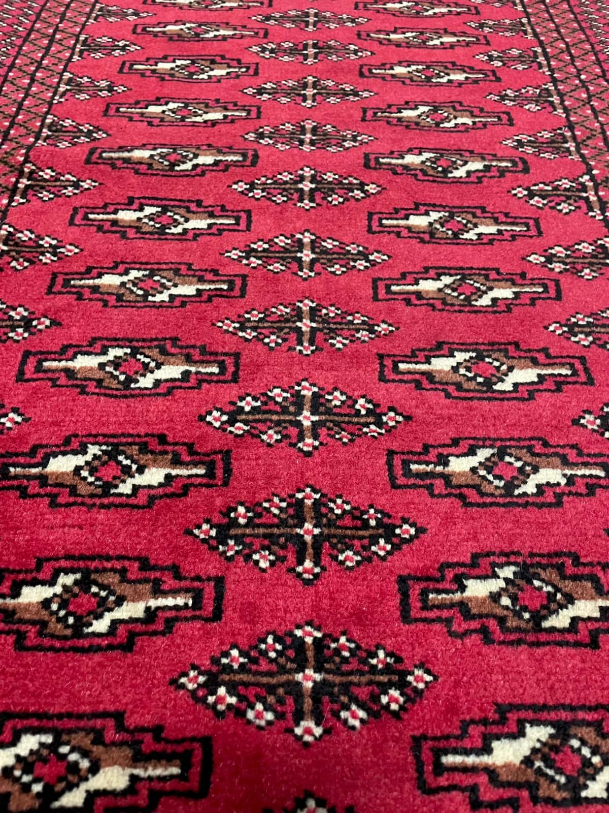 persischer Teppich im turkmenischer Stil in den Maßen 122 Zentimeter Länge mal 80 Zentimeter Breite mit überwiegend rot Farben — Nahaufnahme der Textur