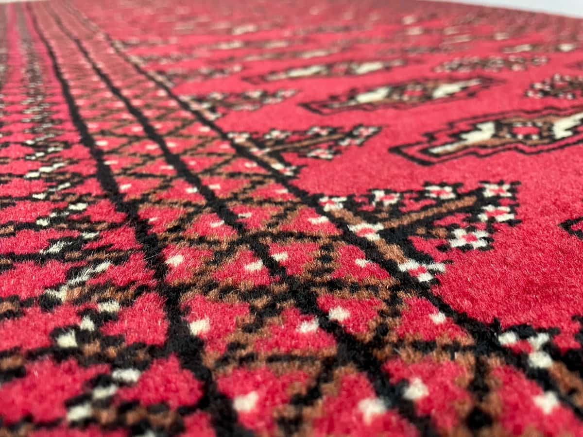 persischer Teppich im turkmenischer Stil in den Maßen 122 Zentimeter Länge mal 80 Zentimeter Breite mit überwiegend rot Farben — Nahaufnahme der Textur
