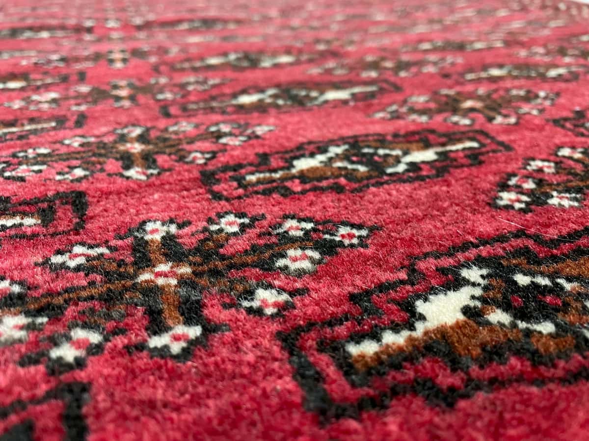Persian rug of Turkoman style in dimensions 110 centimeters length by 83 centimeters width with mainly red colors — Texture close-up