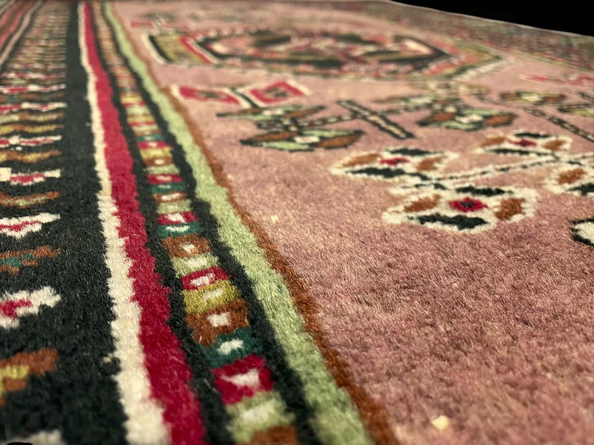 Persian rug of Turkoman style in dimensions 142 centimeters length by 96 centimeters width with mainly pink colors — Texture close-up
