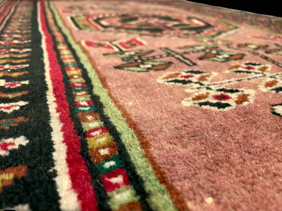 persischer Teppich im turkmenischer Stil in den Maßen 142 Zentimeter Länge mal 96 Zentimeter Breite mit überwiegend rosa Farben — Nahaufnahme der Textur