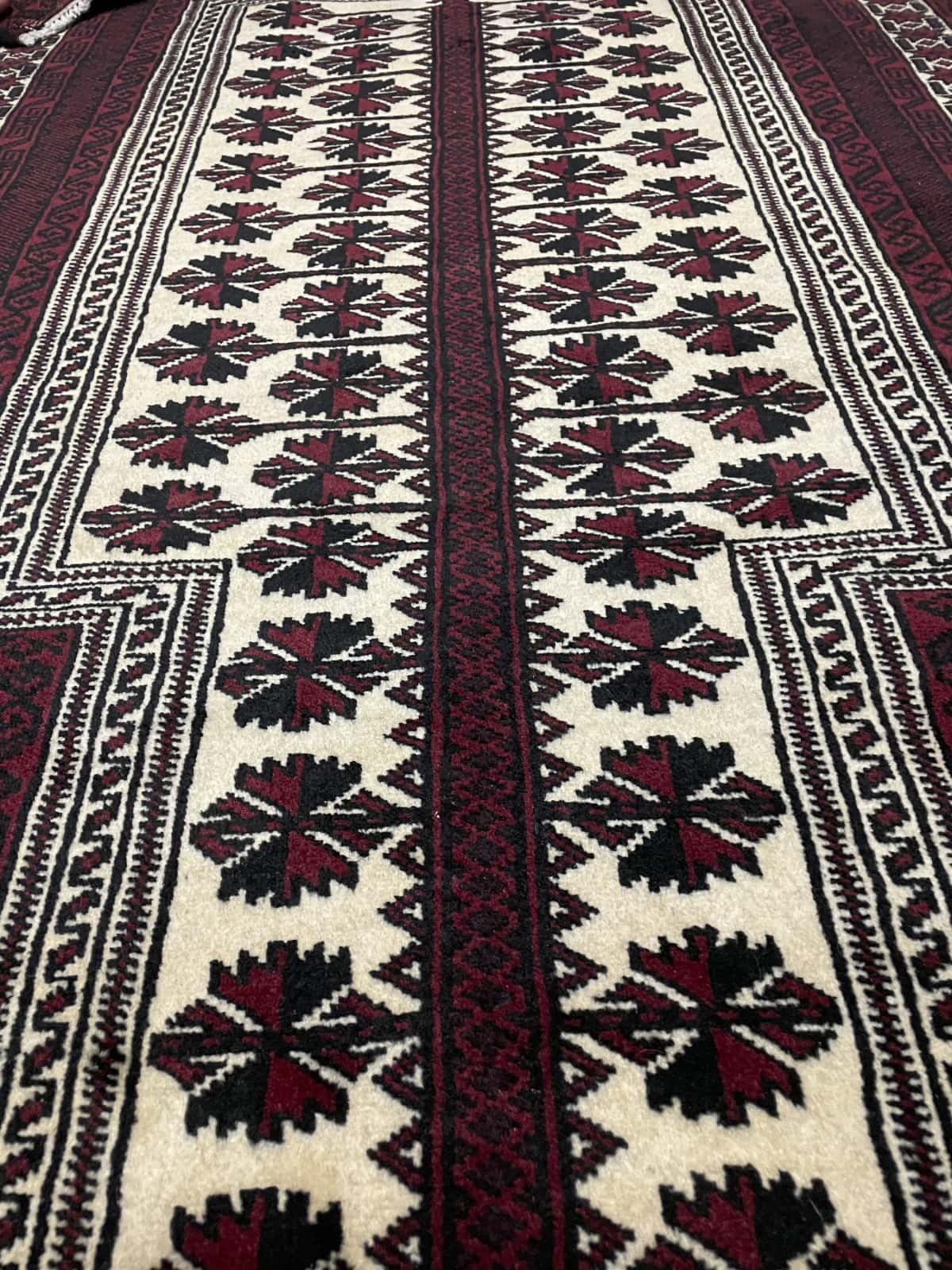alfombra persa de estilo turcomana en dimensiones 150 centímetros de largo por 110 centímetros de ancho con colores principalmente rojo y negro — Primer plano de la textura