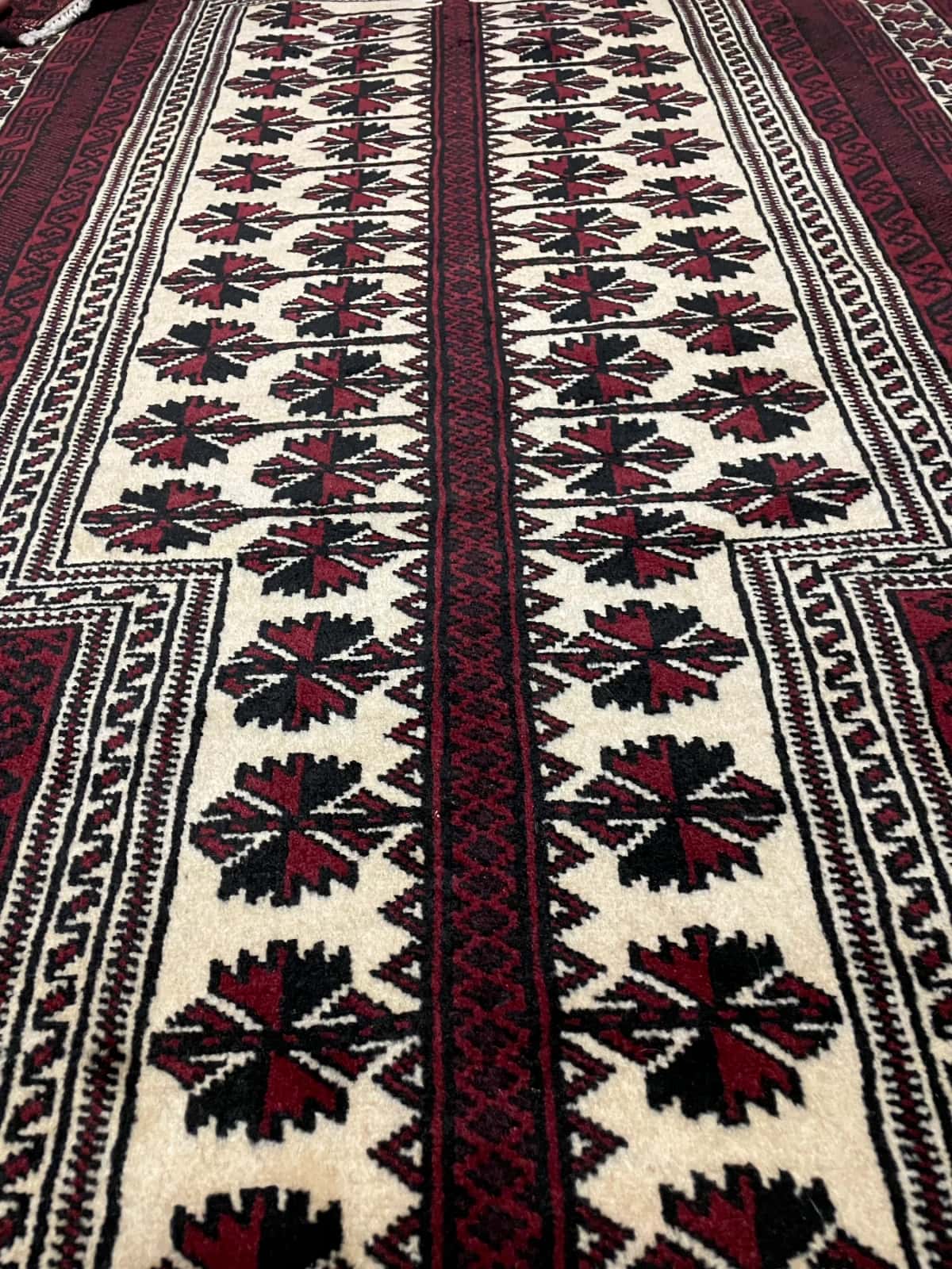 alfombra persa de estilo turcomana en dimensiones 150 centímetros de largo por 110 centímetros de ancho con colores principalmente rojo y negro — Primer plano de la textura