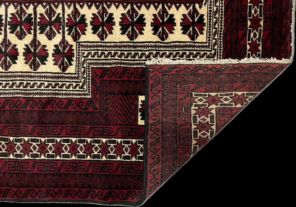 alfombra persa de estilo turcomana en dimensiones 150 centímetros de largo por 110 centímetros de ancho con colores principalmente rojo y negro — Plegada