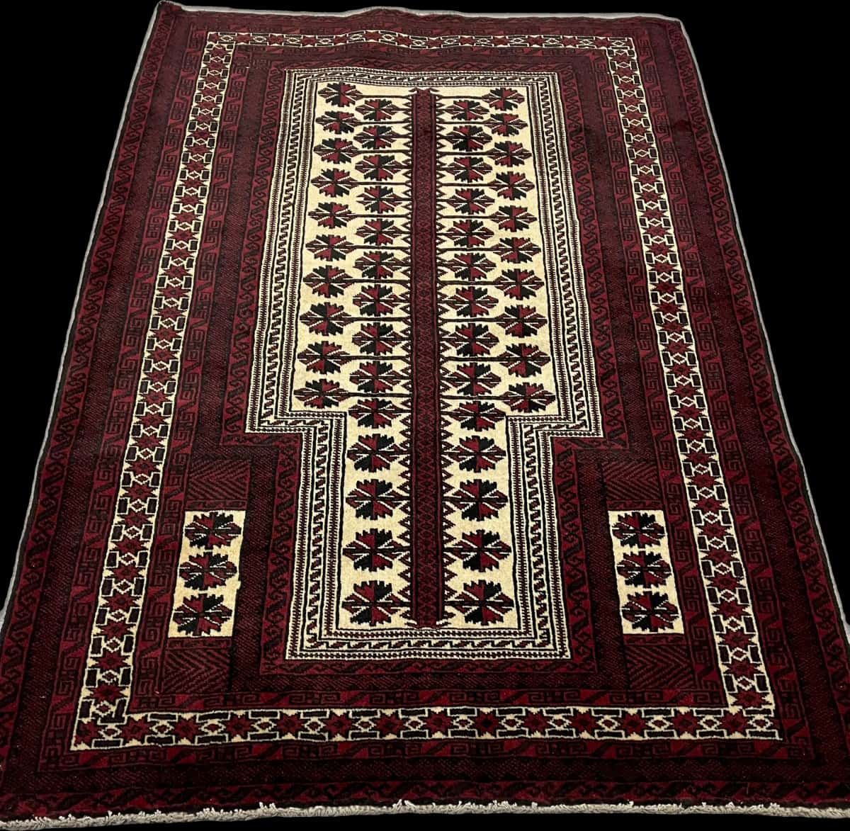 alfombra persa de estilo turcomana en dimensiones 150 centímetros de largo por 110 centímetros de ancho con colores principalmente rojo y negro — Perspectiva